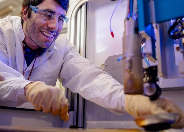 Someone doing research and smiling while wearing a lab coat