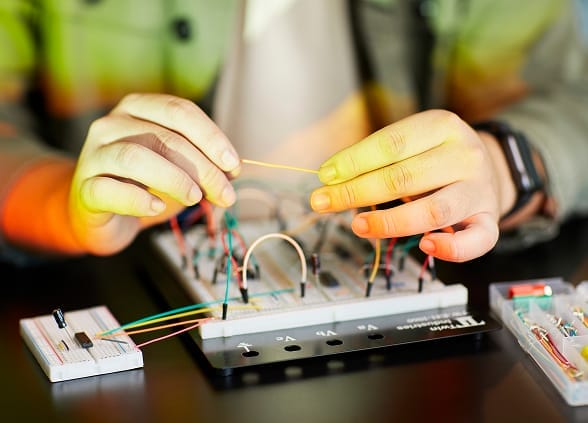 Someone holding wires with hands in a small machine.